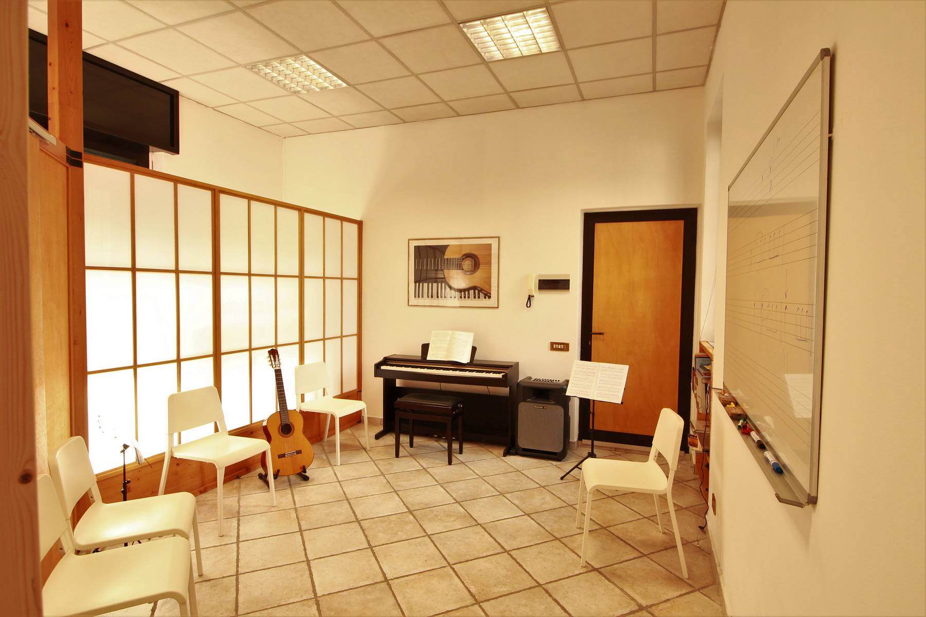 Un'aula di musica con una chitarra e un pianoforte, pronti per essere suonati