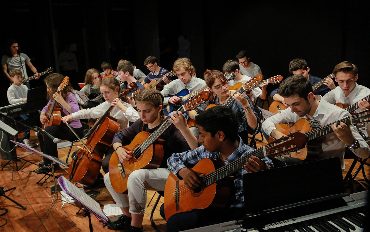 gruppo di studenti di musica che si esibiscono in un concerto di laurea in una sala di teatro.