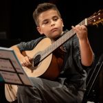 Un giovane studente che suona uno strumento musicale durante un concerto di presentazione