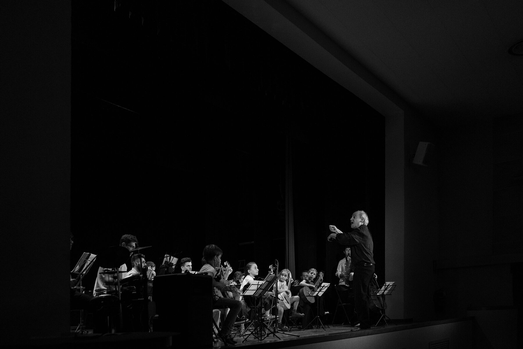 gruppo di studenti di musica che si esibiscono in un concerto di laurea in una sala di teatro.